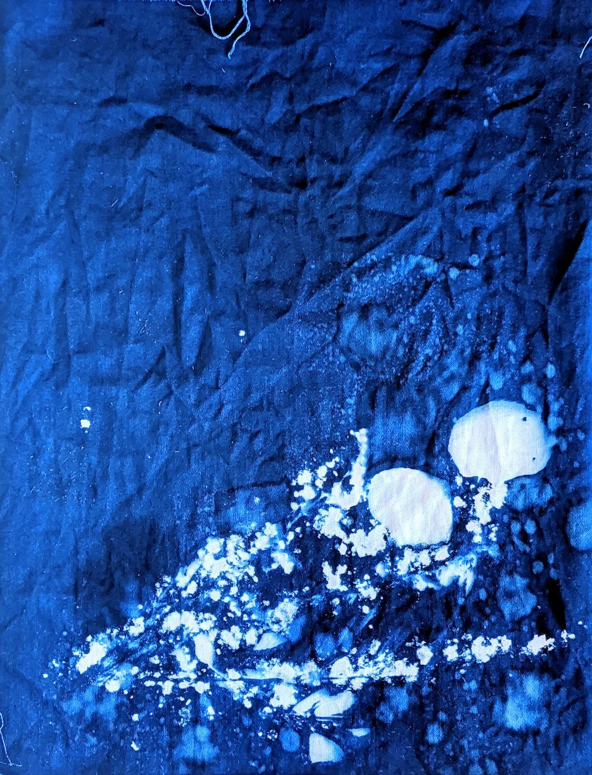 Close-up of a dark, textured surface with white paint splatters and two round white objects on the right side.