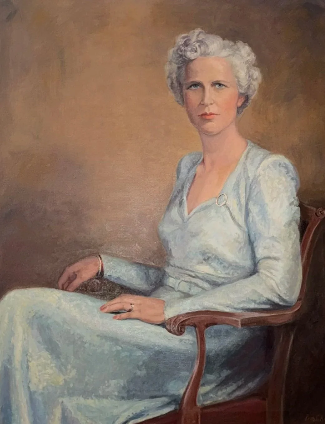 A painting of an older woman with short, curly gray hair sitting on a wooden chair, wearing a light blue dress with a clasp detail on the shoulder, looking directly at the viewer with a neutral expression.