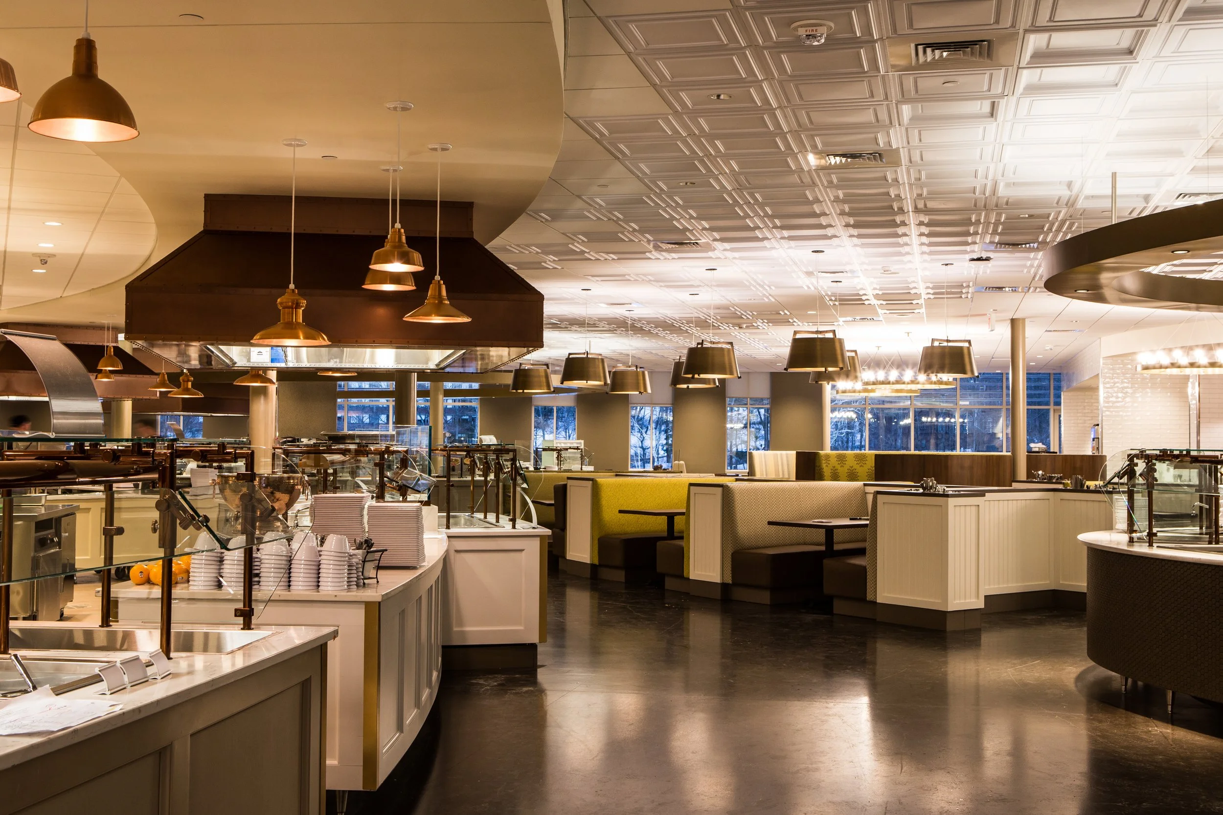 Empty restaurant with booth seating, pendant lights, buffet area, and windows showing outdoor scene