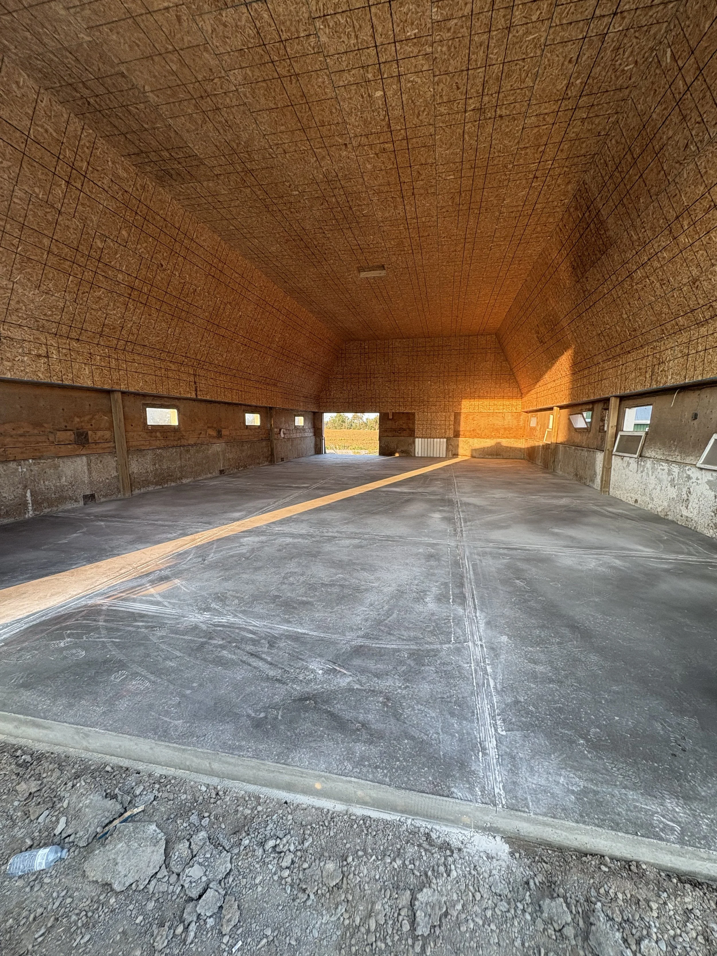 Construction site in Durham Region with a large, arched concrete tunnel and small rectangular windows along the bottom, sunlight streaming through the openings, and a gravel and dirt foreground.