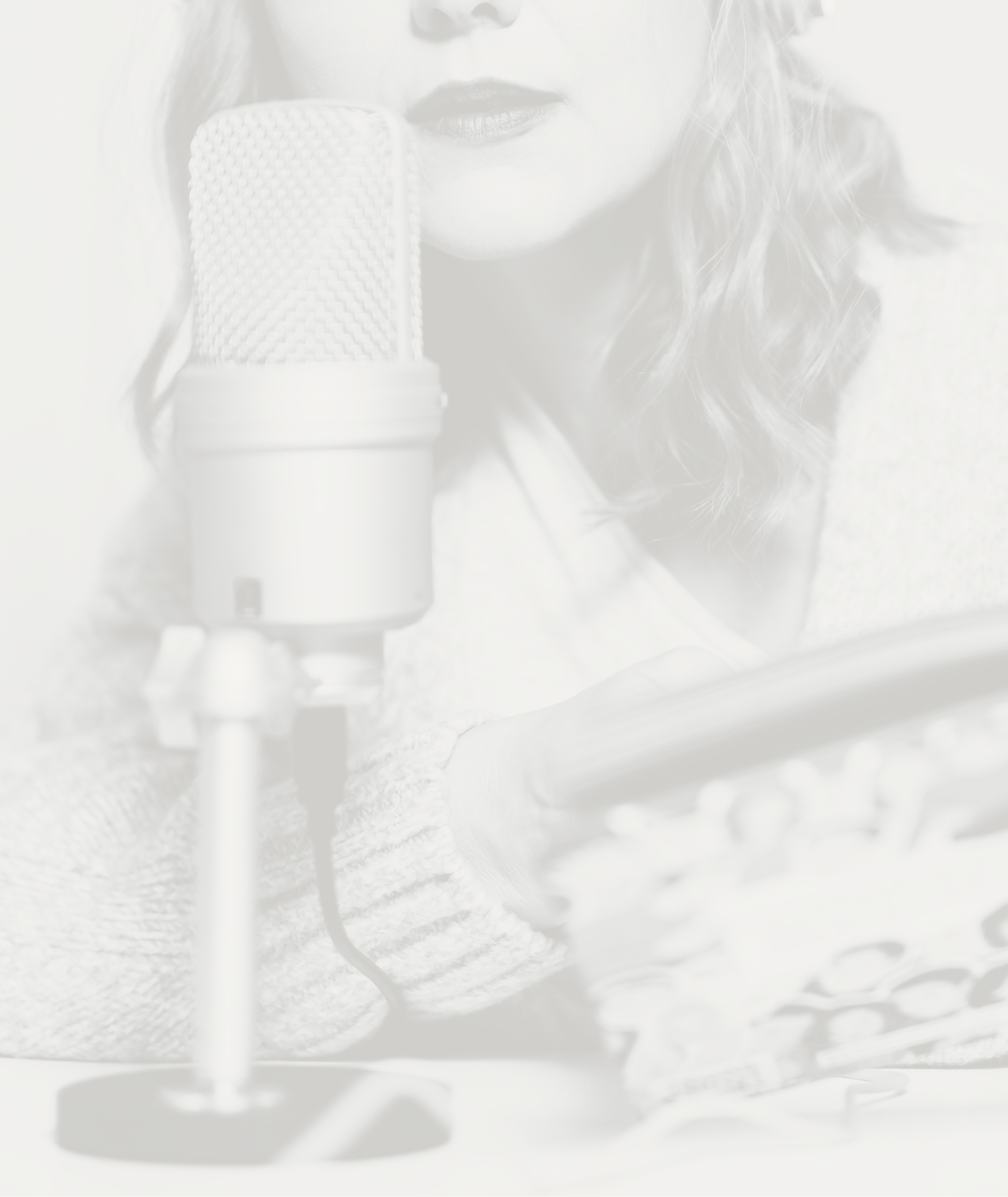 Woman with curly hair speaking into a large microphone with a pop filter, representing voice, storytelling, and intentional communication.