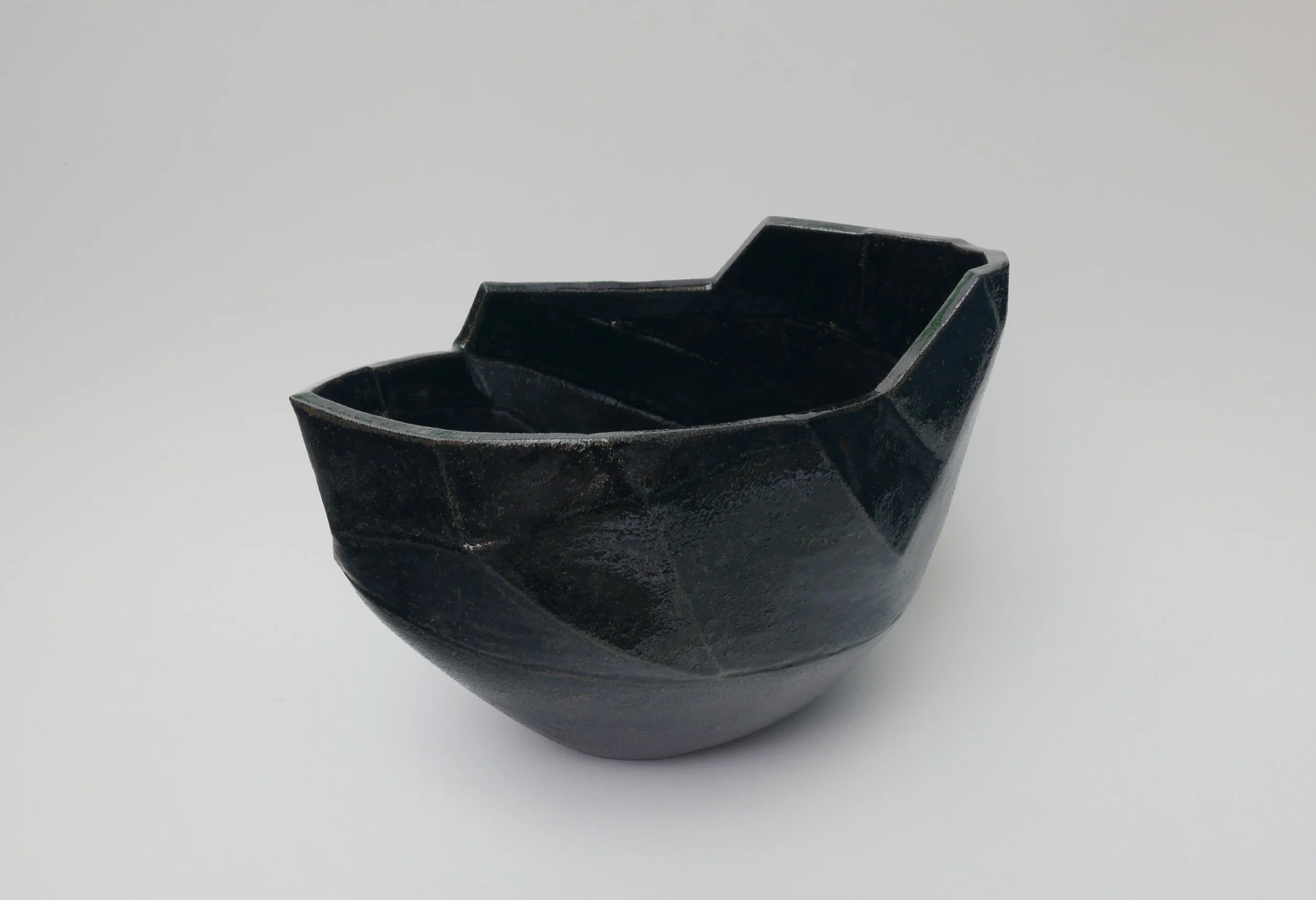 Black bowl with geometric patterns on a white background.
