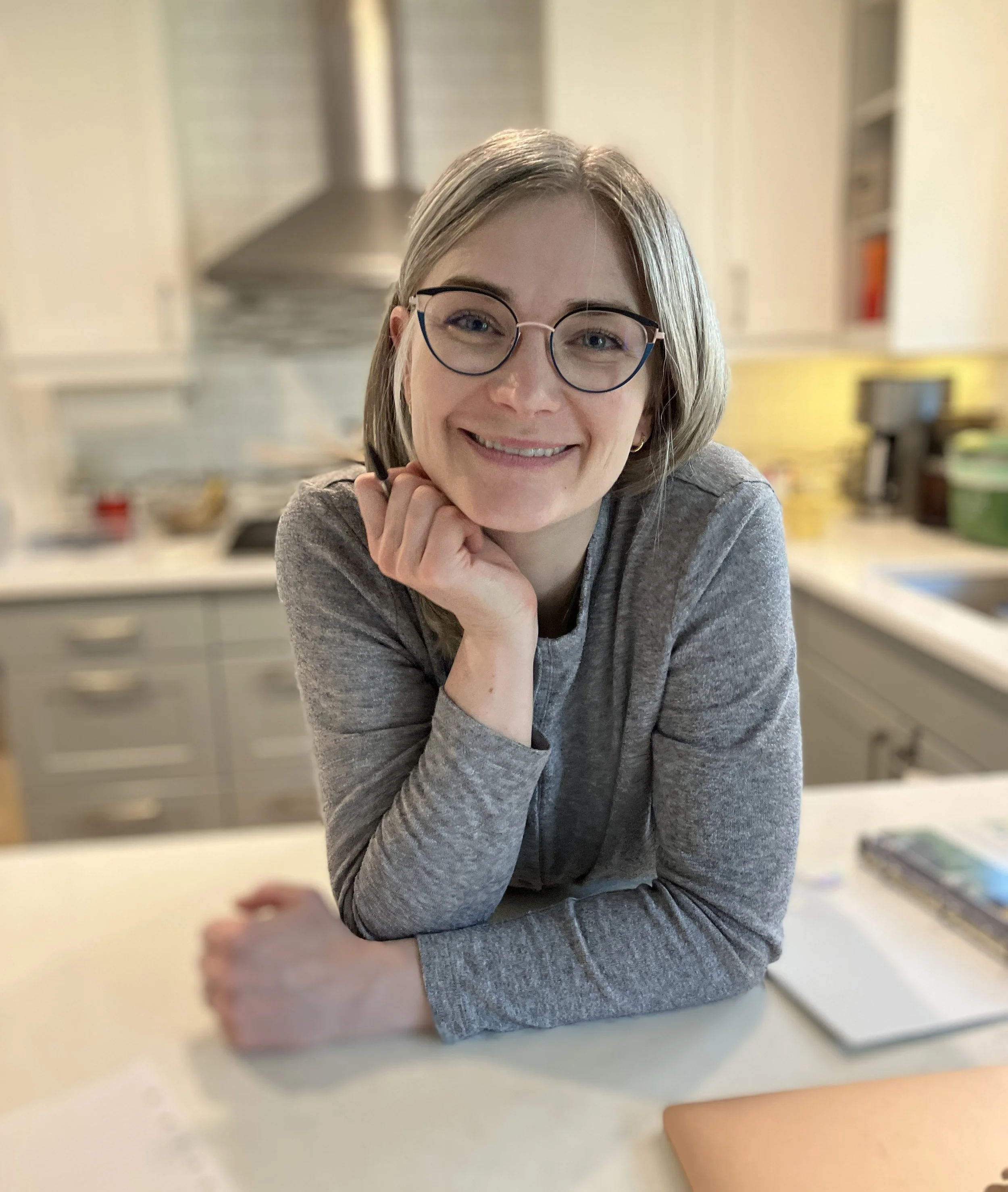 A smiling portrait of Crystal, founder of the art table, sitting at home.