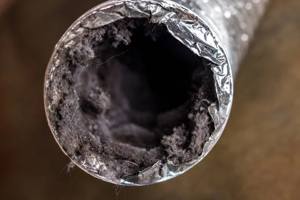 Close-up of the inside of a used aluminum foil roll with black residue.