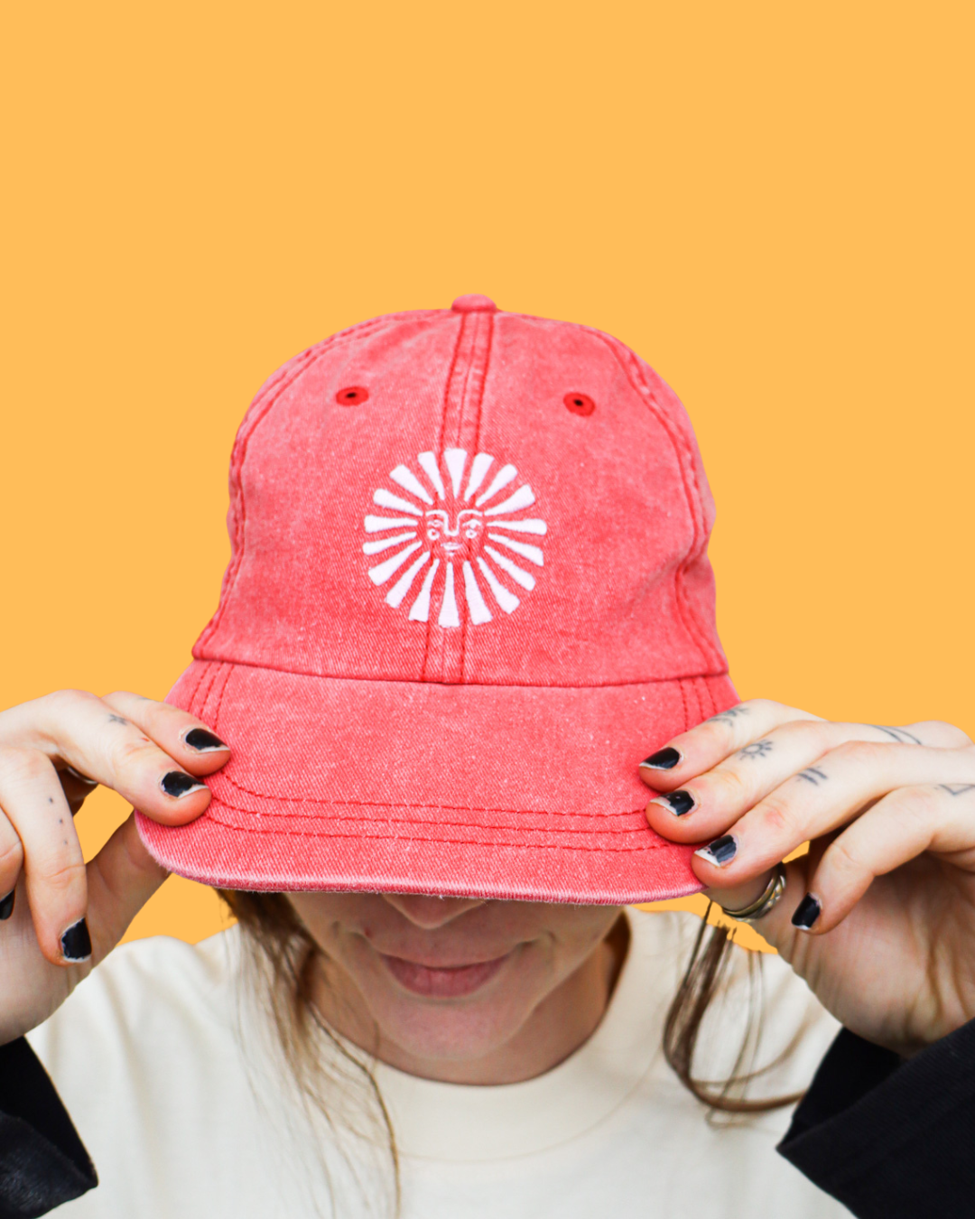 A woman with a pink Empire hat against a yellow background.