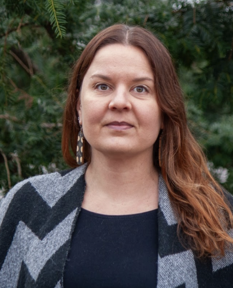 YKES:n jäsen Tiina Ollila kuvattuna ulkona, taustalla tummanvihreitä puita.