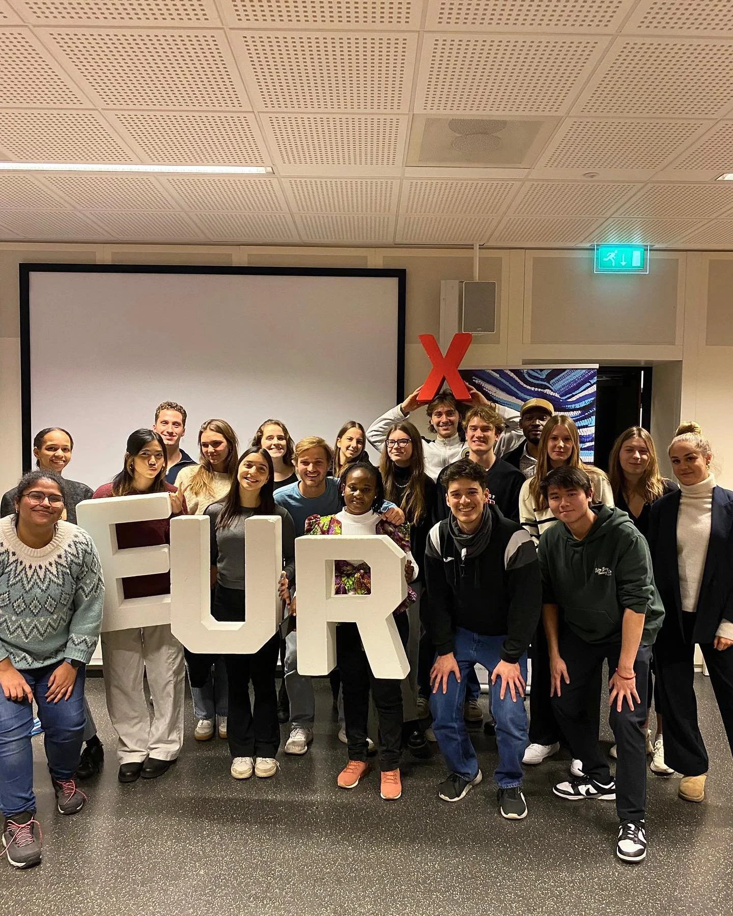 A big group of Erasmus University students posing with large EUR letters