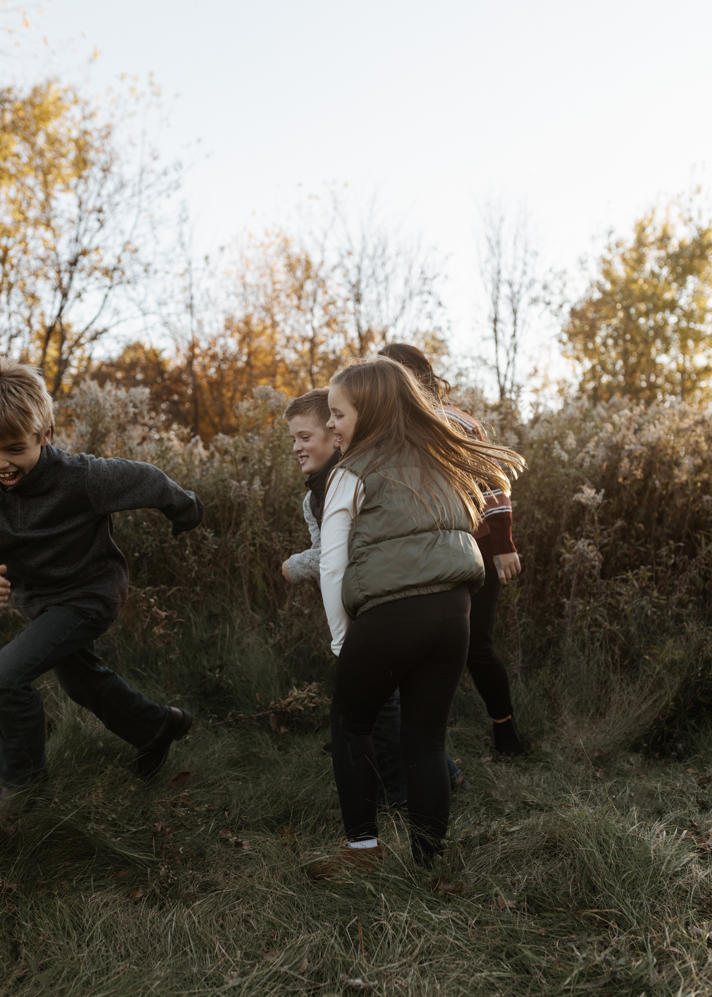 Children playing and having fun outdoors during autumn, surrounded by trees with fall foliage.