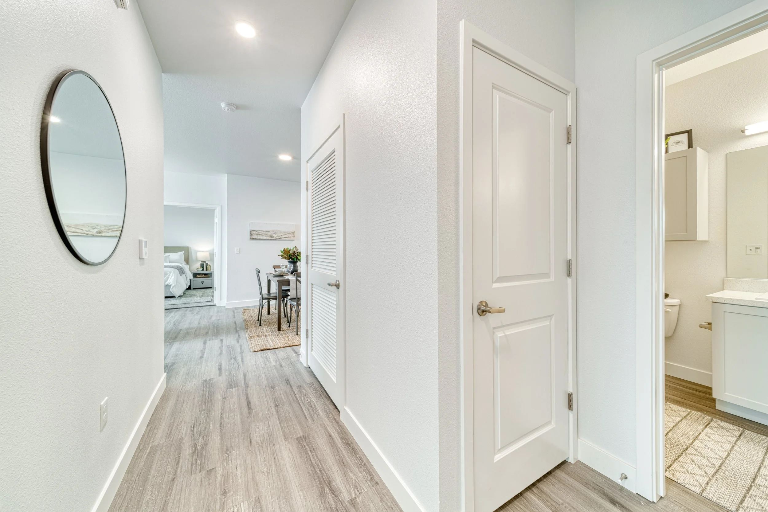 Interior view of a luxury modern apartment hallway leading to living and bedroom areas, with a bathroom visible on the right.