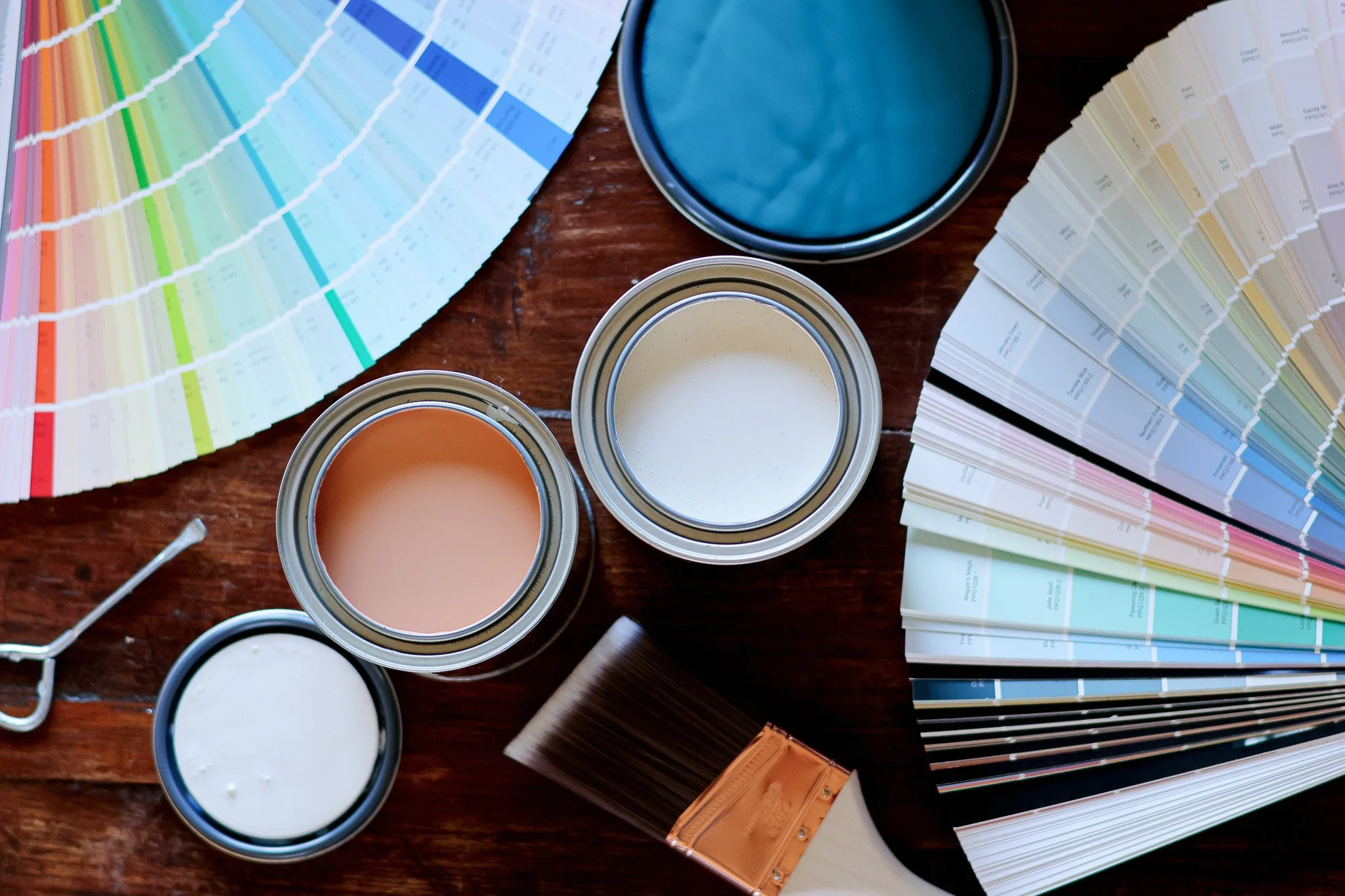 Color paint swatches, paint cans, and paint color sample cards on a wooden surface.