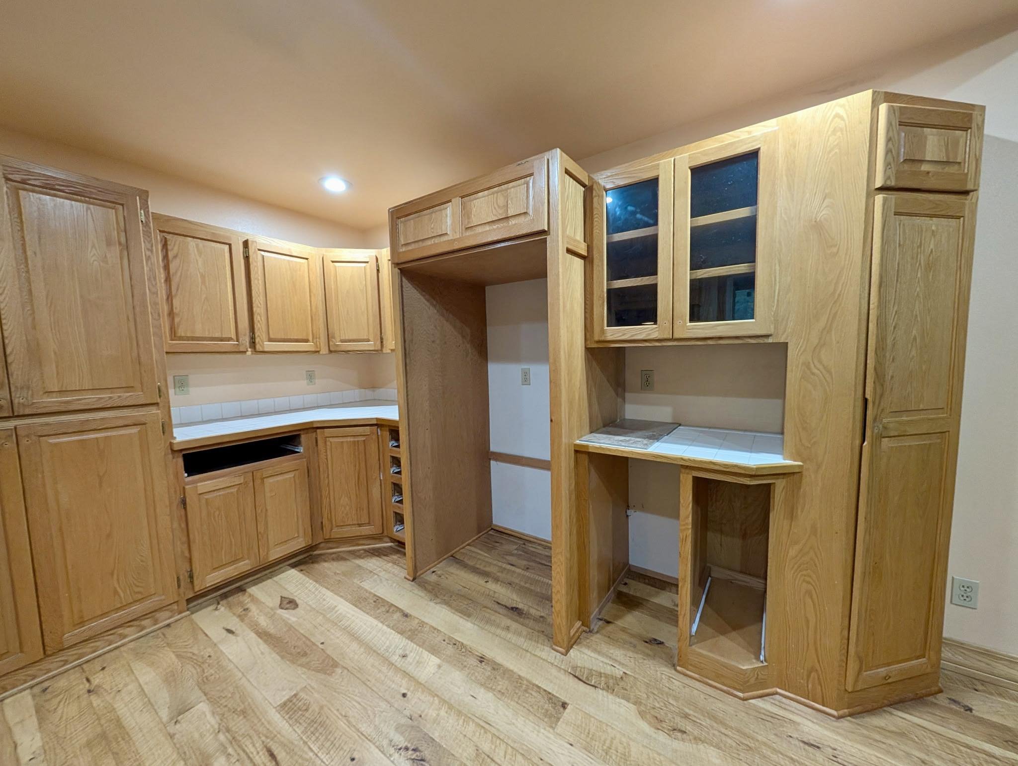 Kitchen remodel in progress with wood cabinetry, hardwood flooring, and interior finish work.