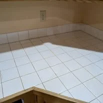 Kitchen remodel detail showing tile countertop, backsplash, and electrical outlet installation.