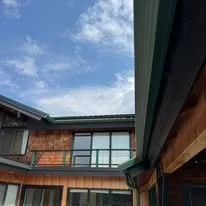 Exterior finish work on a Western Montana home with large windows, wood siding, and outdoor deck area.