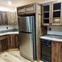 Finished kitchen remodel with stained wood cabinets, tile countertop, refrigerator, and stove.