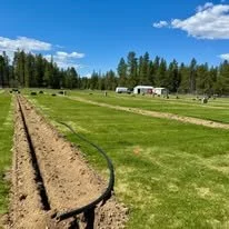 Sprinkler system installation with trenching along a landscaped property area.