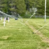 Lawn sprinkler system watering a maintained grass area after irrigation installation and site work.