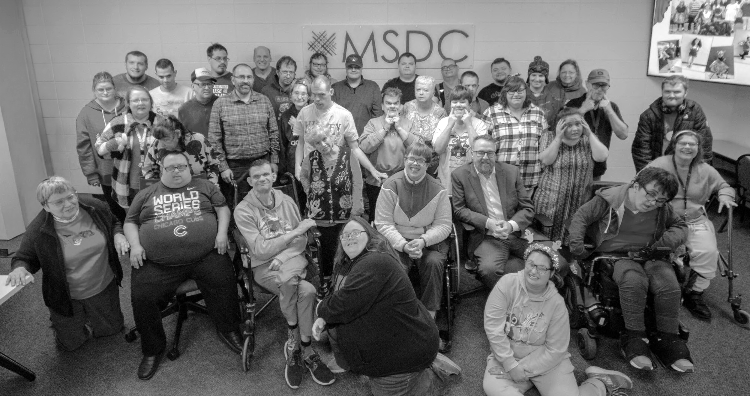 Group of people gathered in a room with a sign that reads MSDBC on the wall behind them.