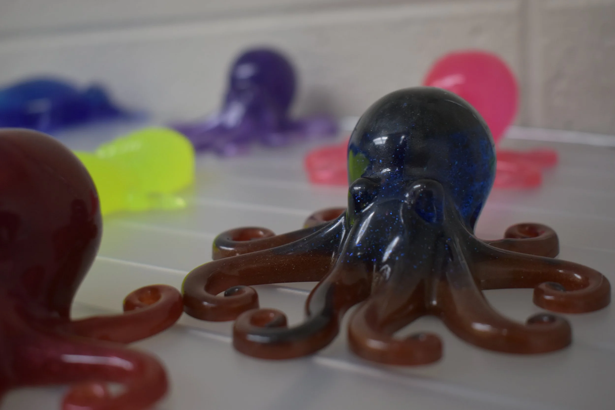 Colorful glass octopus figurines arranged on a white surface.