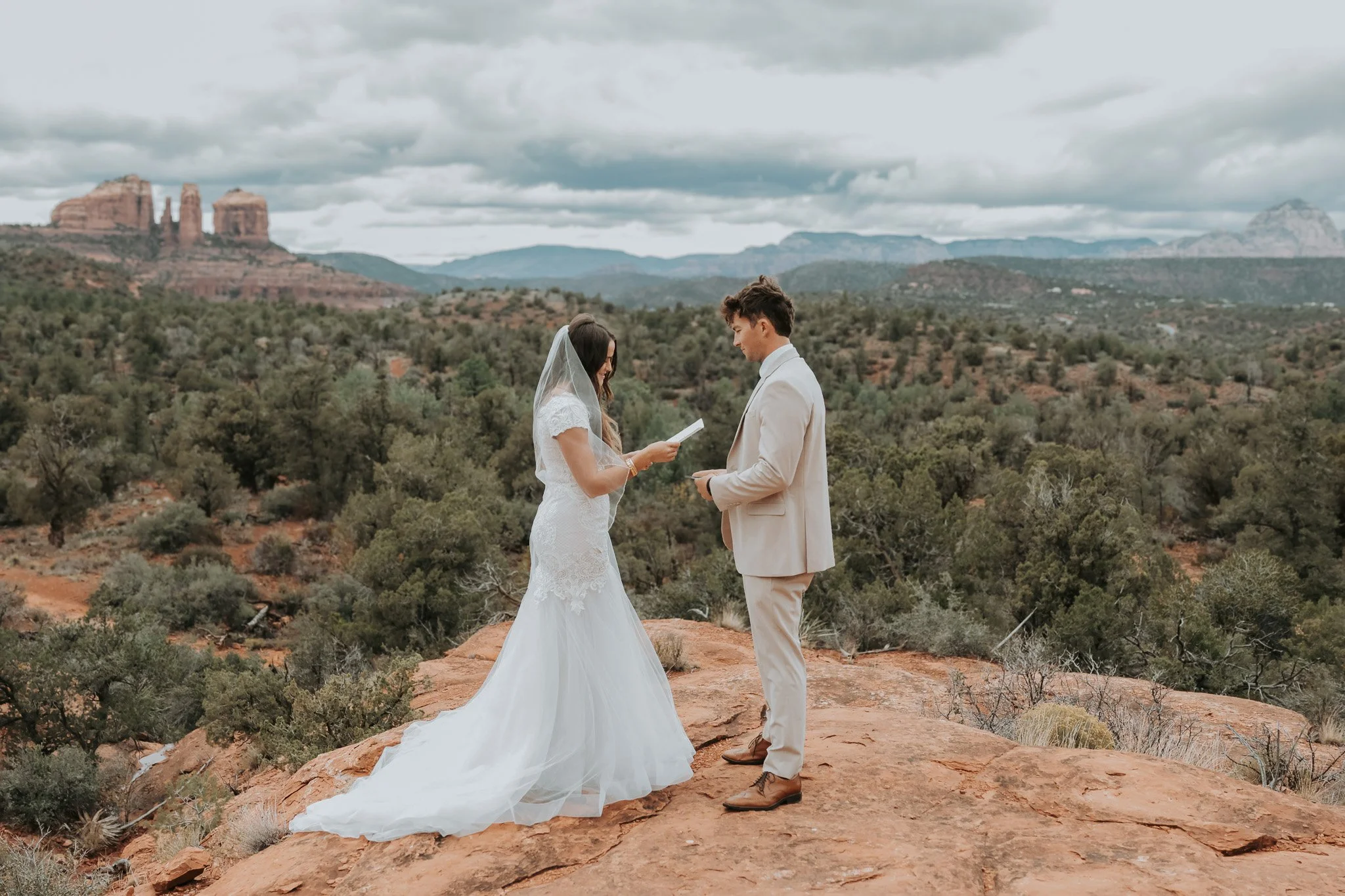 Couple reading vows during a Sedona elopement with a full red rock landscape behind them.