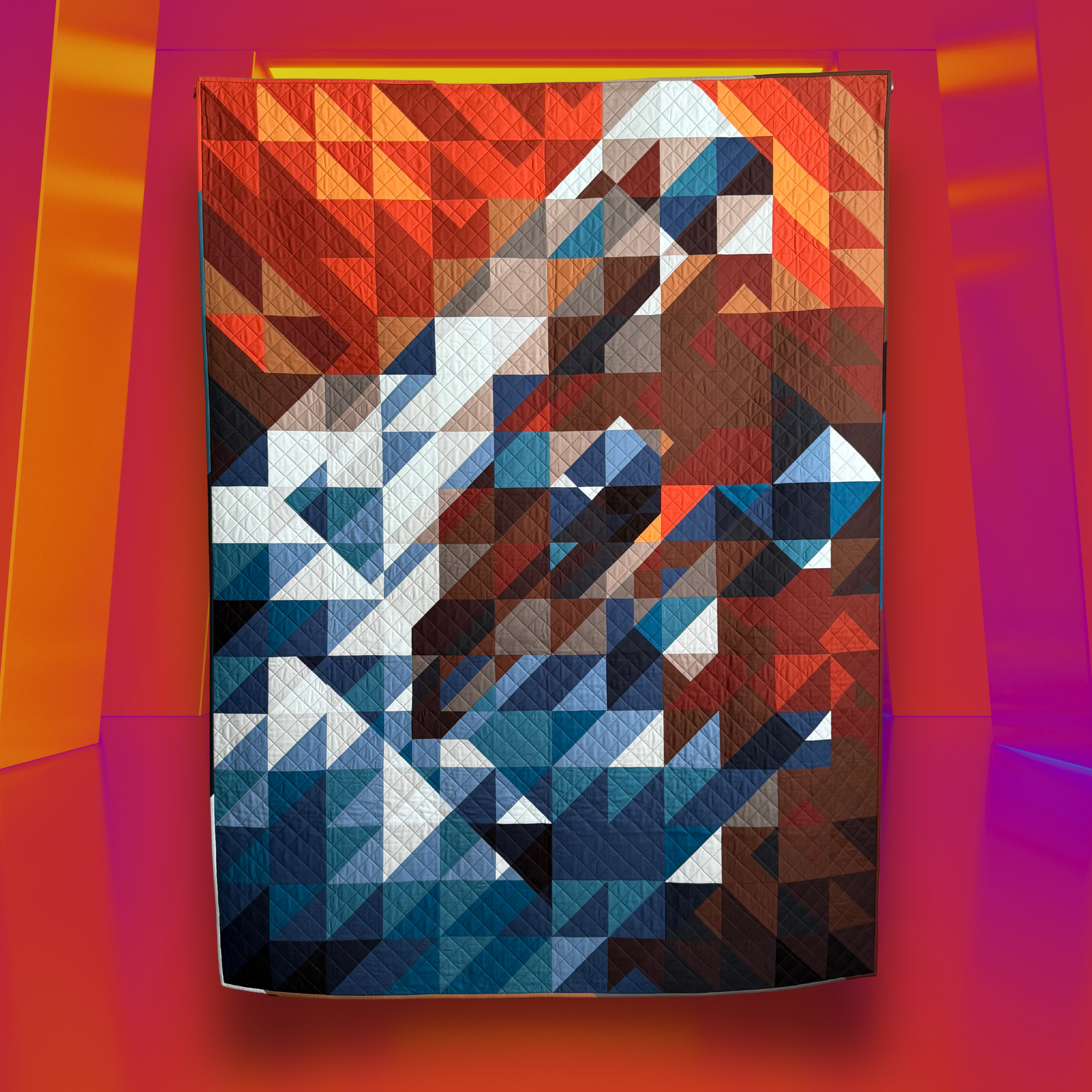 An image of an abstract designed quilt representing Pillars of Creation, a famous photo from the Eagle Nebula. The quilt features an array of red, oranges, blues, grays and browns.