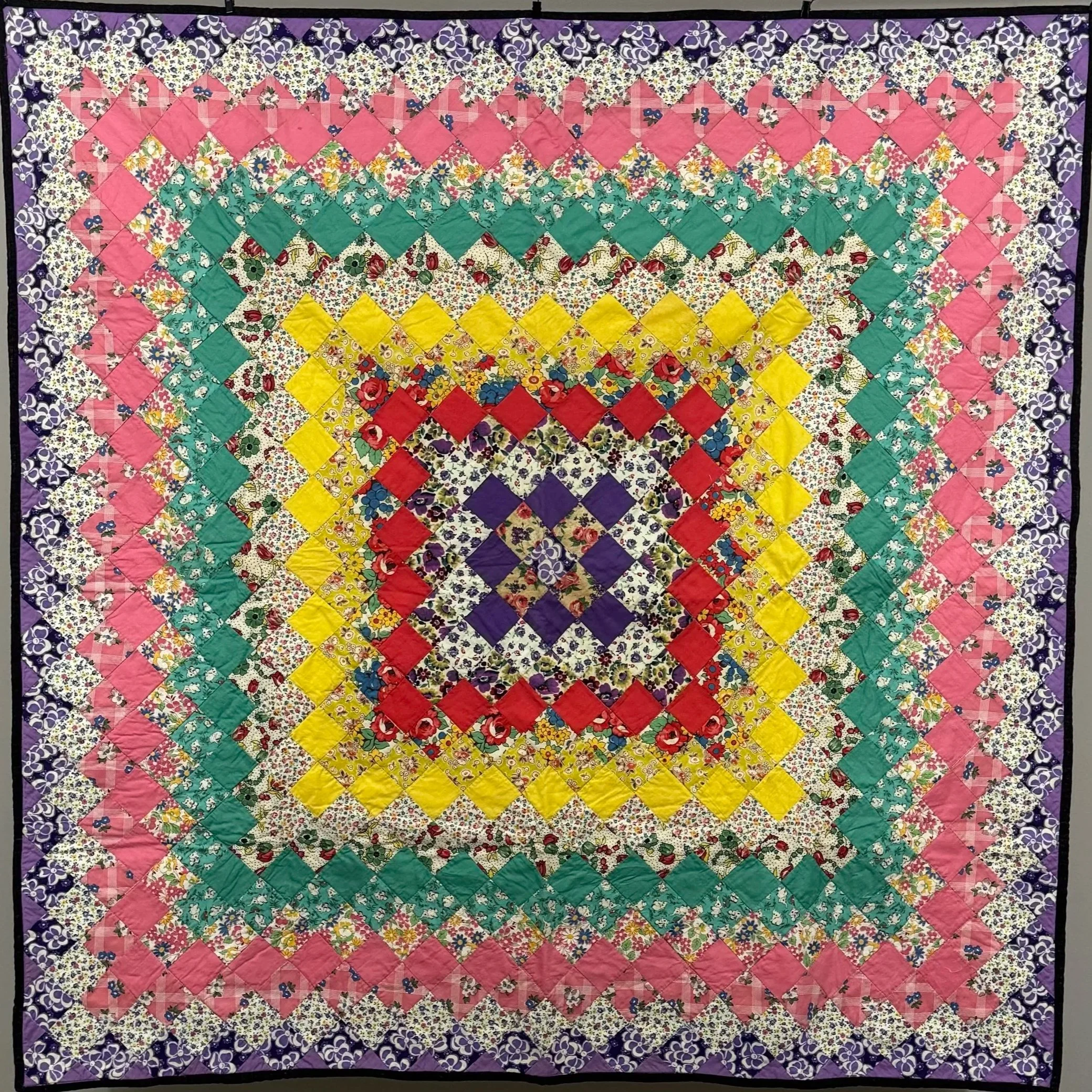 A vintage trip around the world quilt in varying solid and print fabrics of colors.