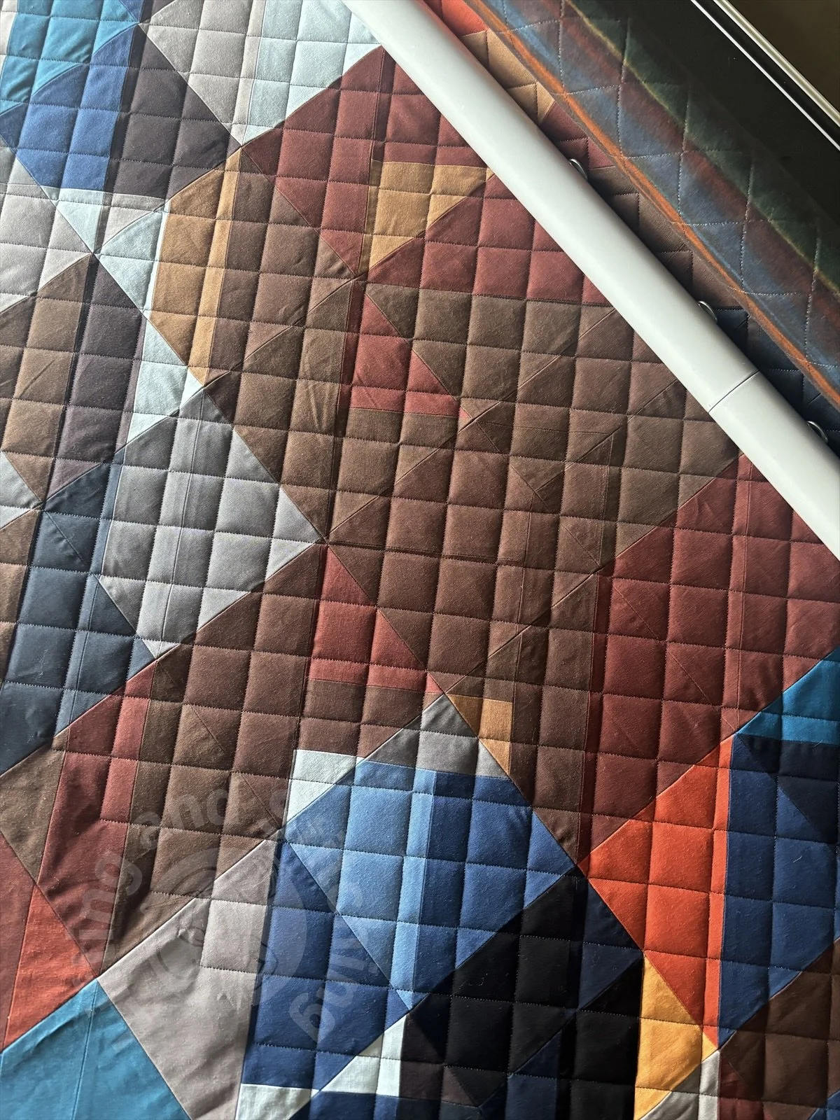 A close up photograph of the quilting in progress. A diagonal cross hatch is quilted edge to edge.