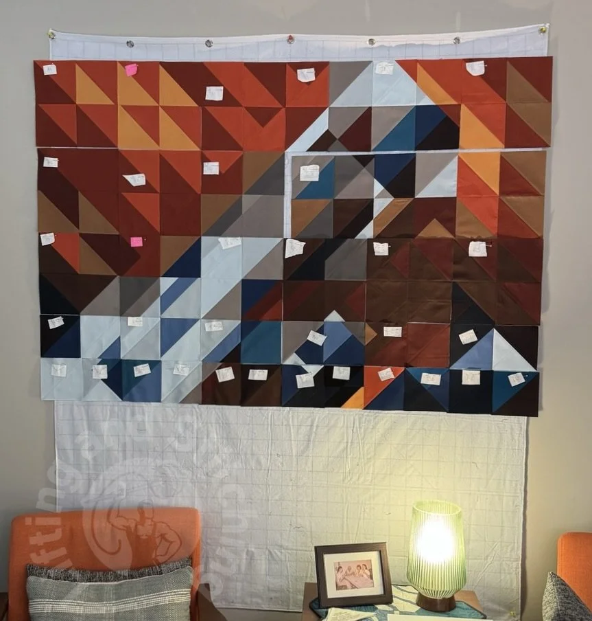 Fabric sewn together placed on a design wall organized by color to create an abstract interpretation of a nebula.