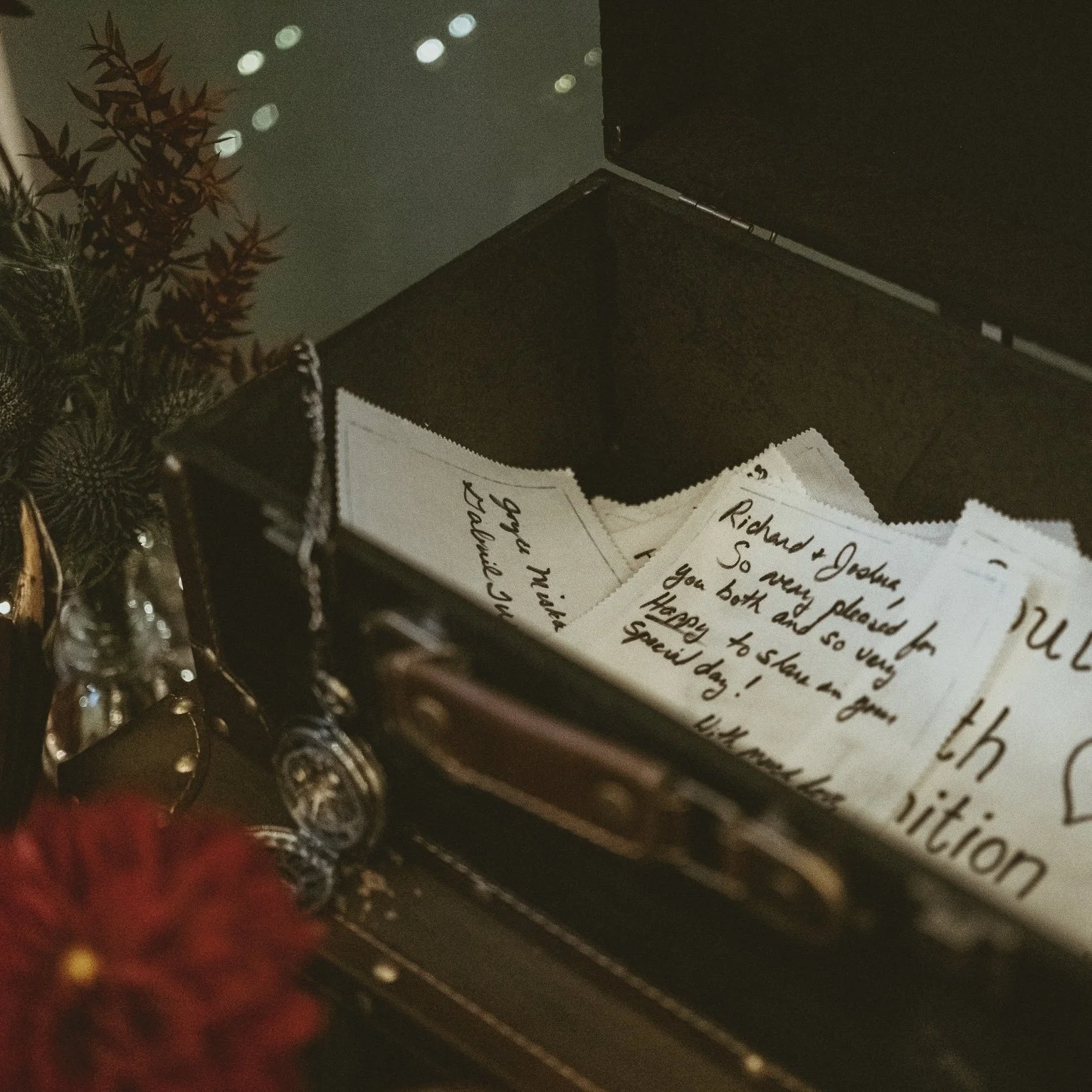 Fabric squares with handwritten wedding guest messages collected in an open wooden keepsake box.