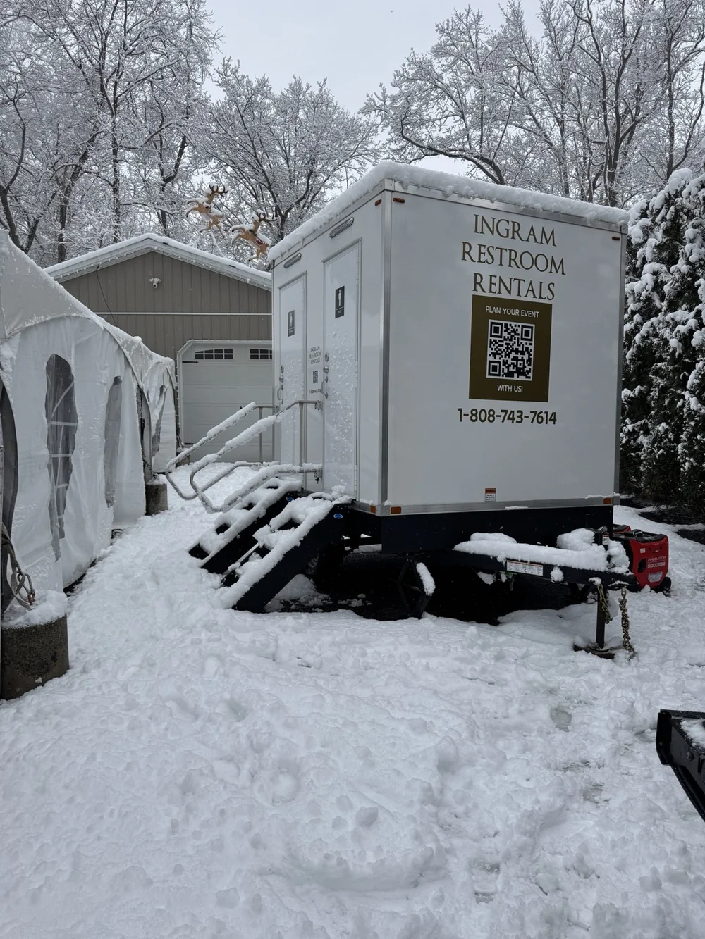 Heated restroom trailer beside an event tent in the snow