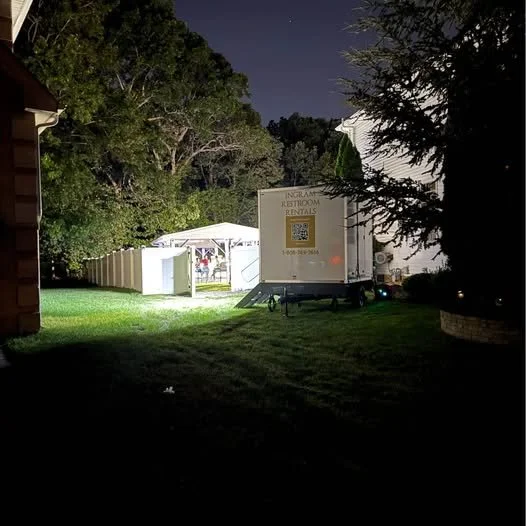 Restroom trailer lit up beside an event tent at night