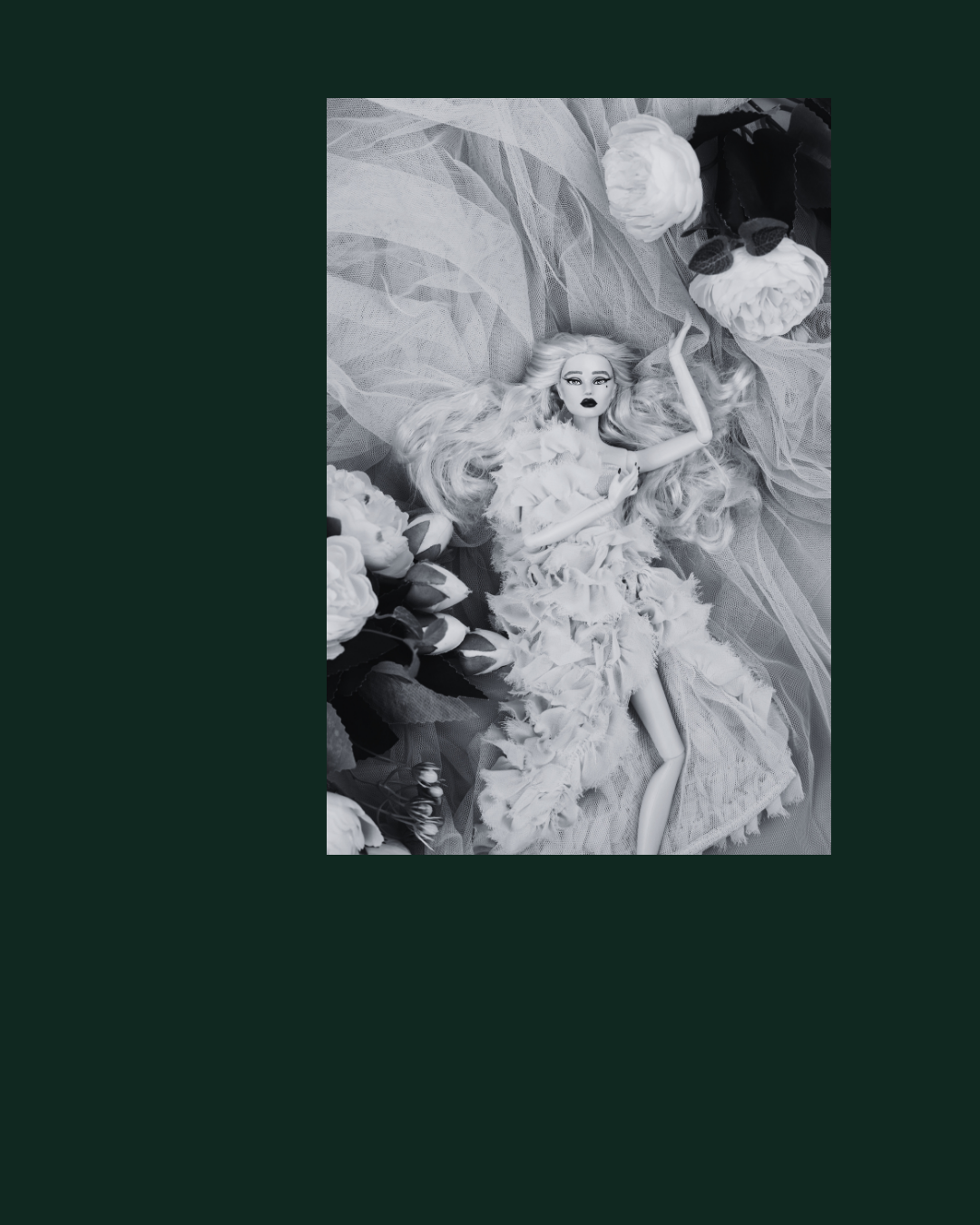 A doll with long, wavy hair lying on layered fabric, surrounded by flowers.