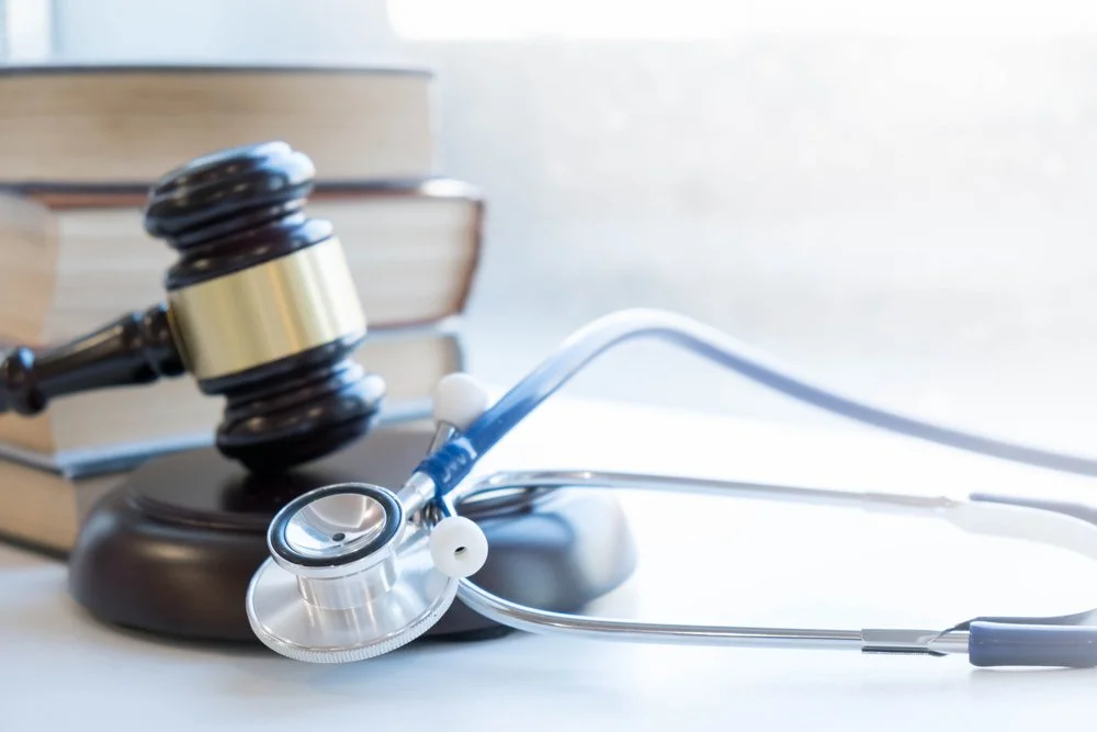 Gavel and wooden stand with a stethoscope and stacked books in the background.