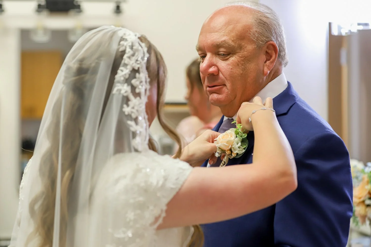 A bride pinning a boutonniere on her father's lapel.