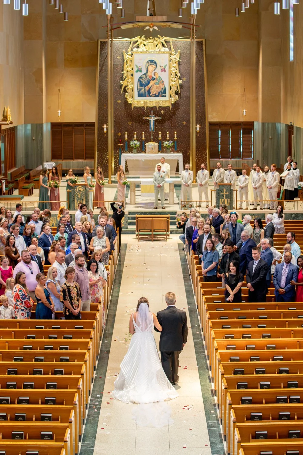 A bride and groom walking down the aisle in a church during their wedding ceremony, with guests seated on either side.