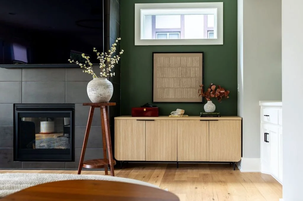 living room with green accent wall, console table with modern art, and a flower pot on a small table