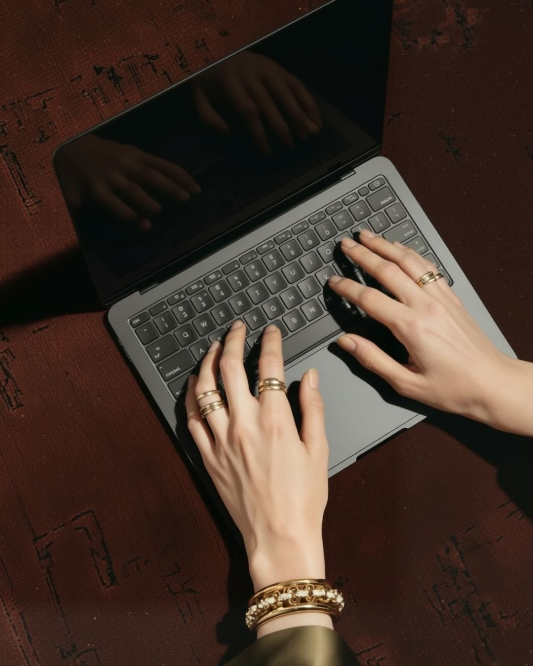 Women typing on a laptop with gold rings