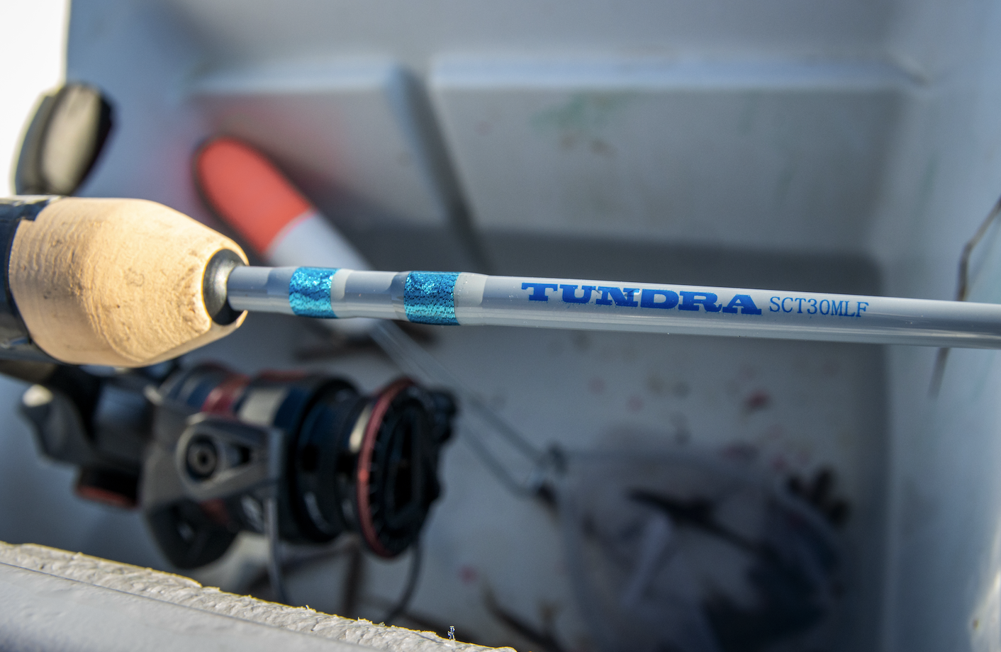 Close-up of a fishing rod labeled 'TUNDRA SCT30MLF' in a tackle box.