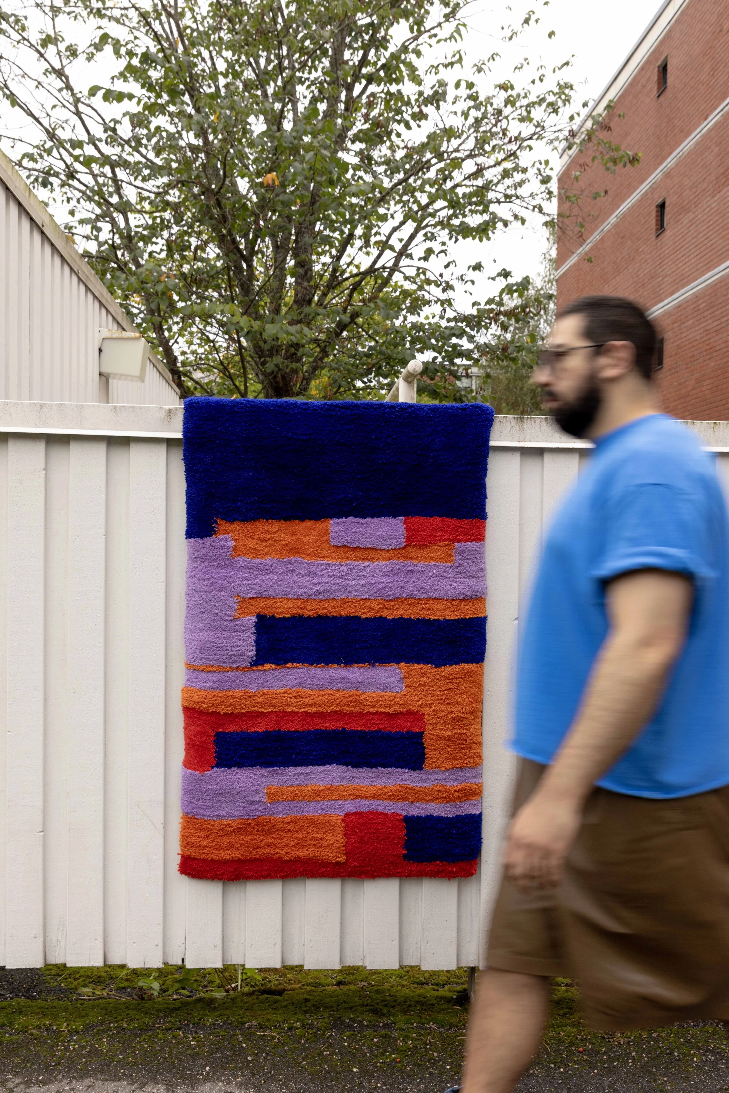 Vastapaikalla oleva abstrakti kude, jossa on pysäköity väripaletti violettia, punaista, oranssia ja sinistä. Taustalla puita ja rakennuksia.