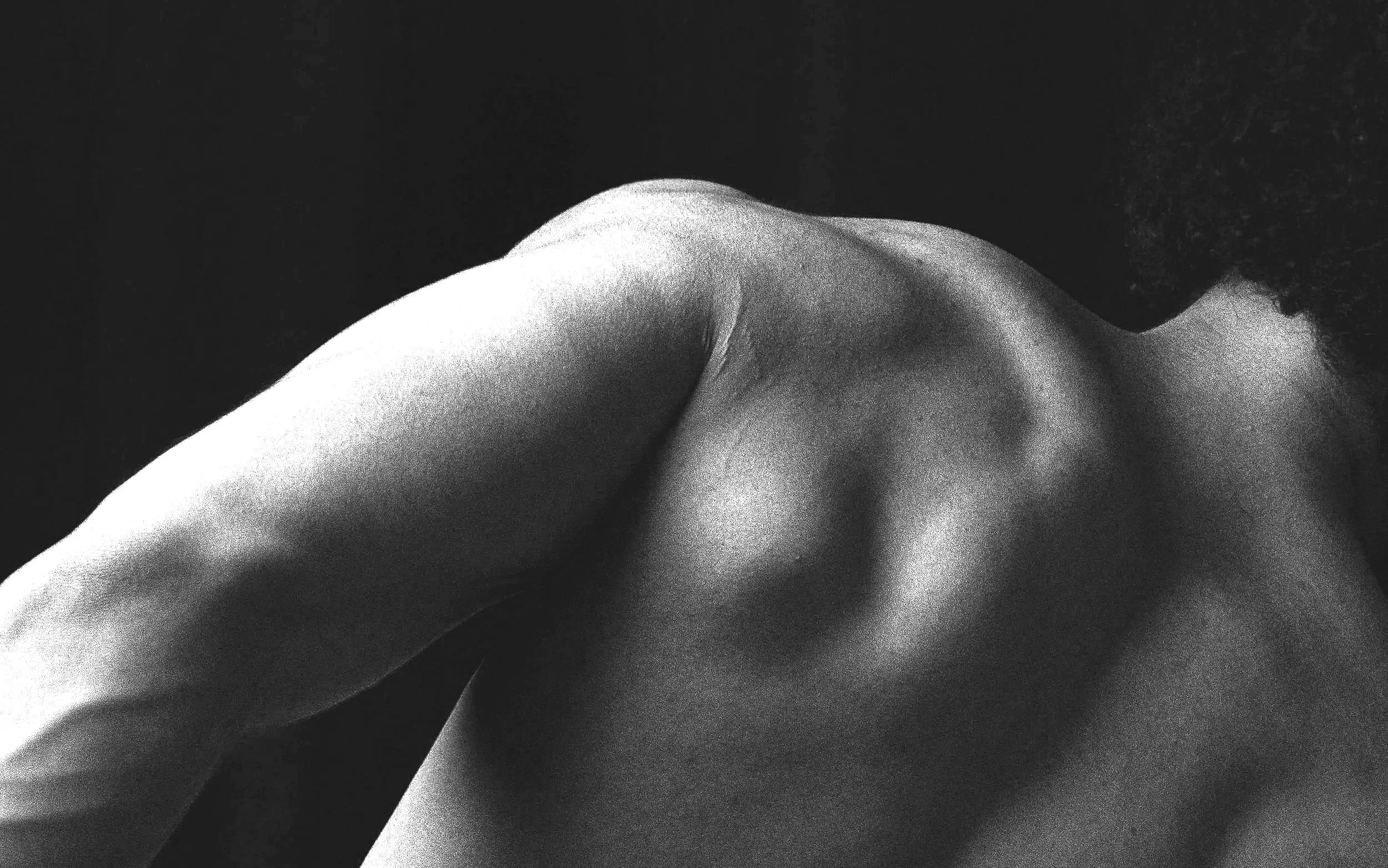 Close-up black and white photograph of a man's bare shoulder and upper back after waxing, with curly hair. Located in Melbourne, Australia. Glenroy, Northern suburbs of Melbourne, Victoria