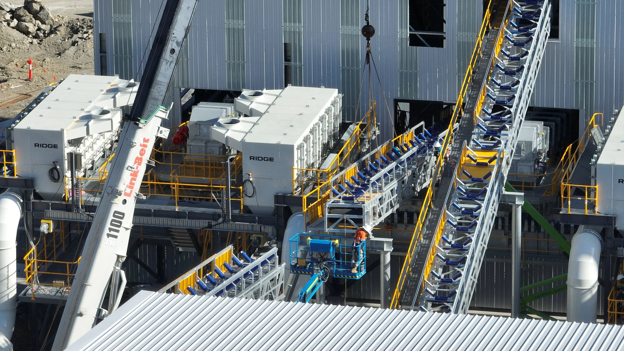 Industrial construction site with cranes, machinery and workers installing equipment