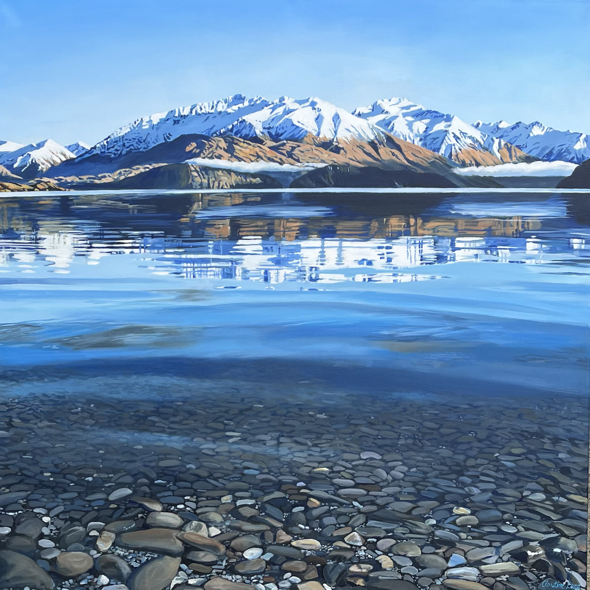 Painting of snow-capped mountains reflected on the calm blue lake with a rocky shoreline in the foreground.