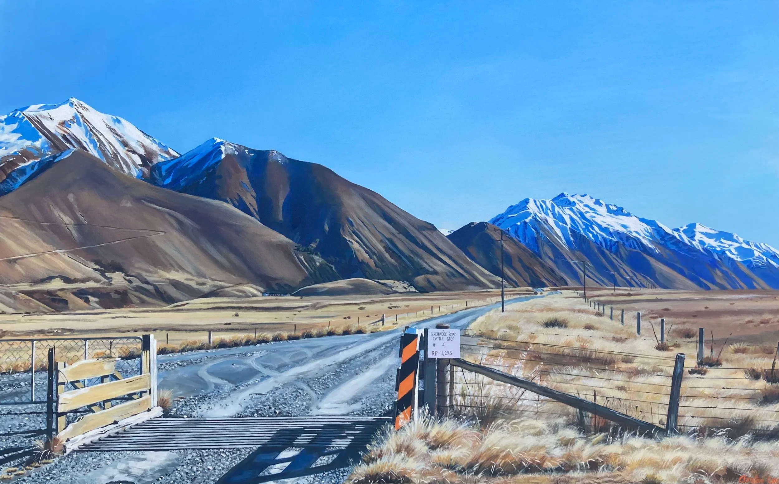 A mountain landscape with snow-capped peaks, a dirt road, a wooden gate, and a fence in a wide open field.
