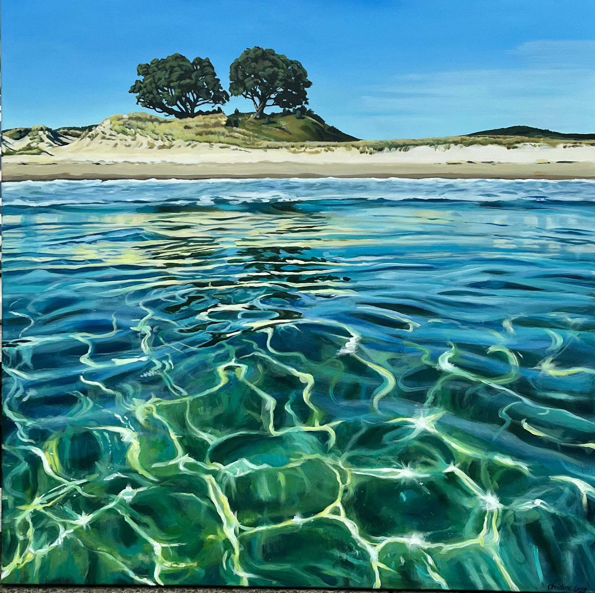 A painting of a coastal scene with clear blue water in the foreground, a sandy shoreline, and green trees on a hill under a bright blue sky.