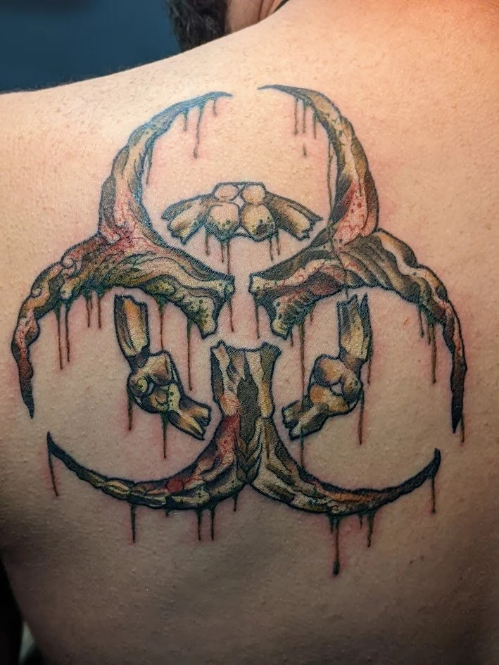 Tattoo of a skull with a bee at the top, with melted and dripping effects on the skull and bee, on a person's back.