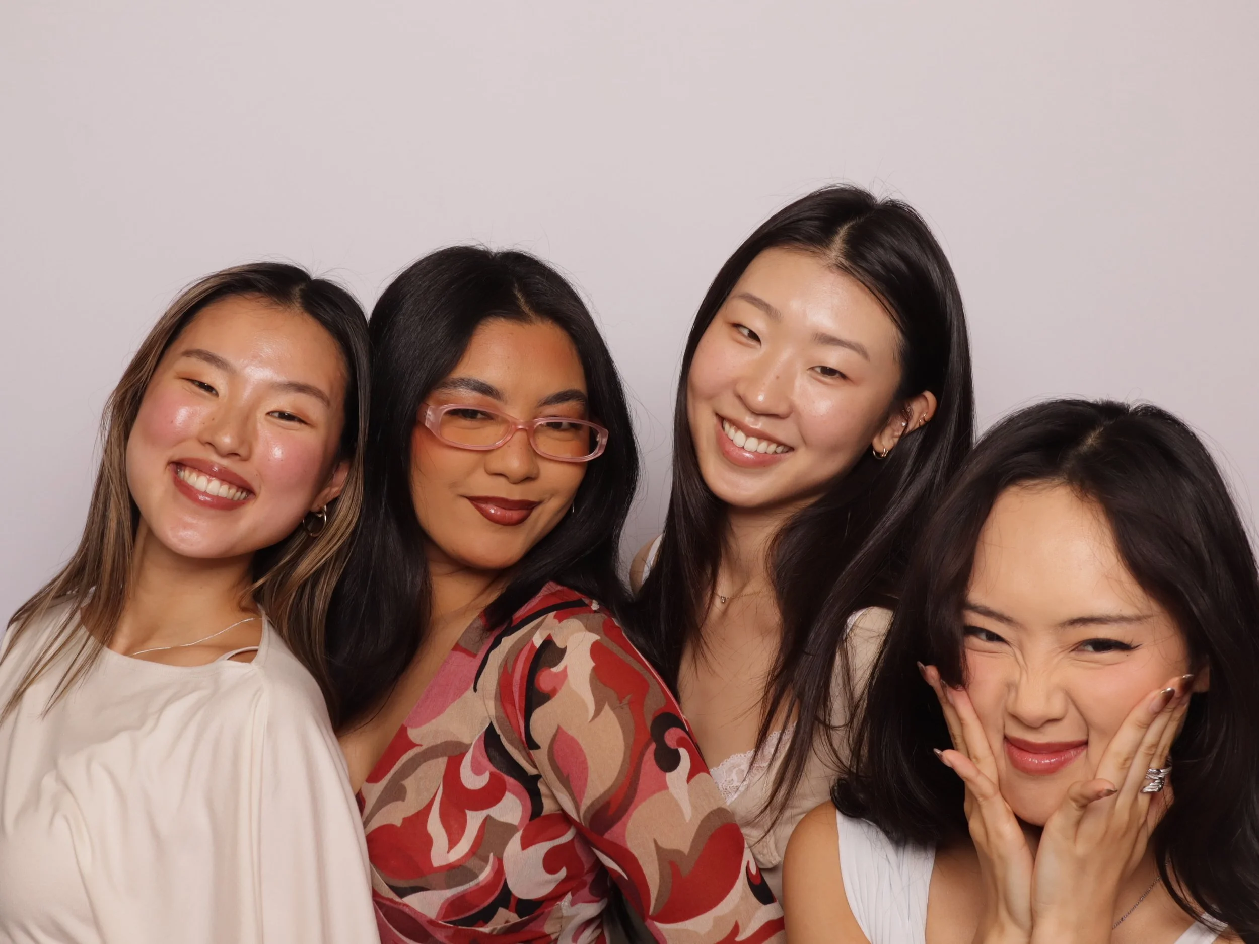 Four women smiling and posing together against a plain white background.