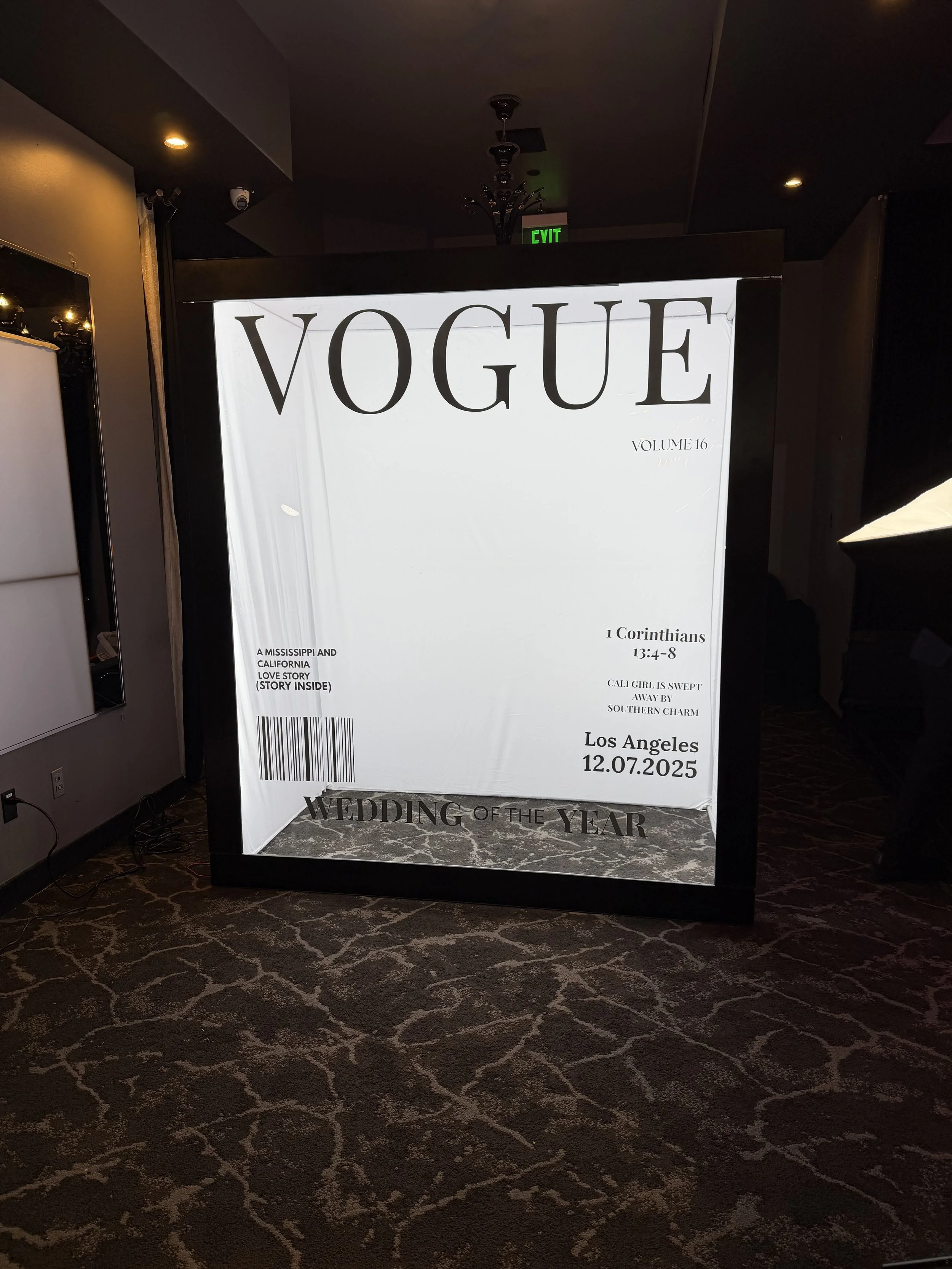 A Vogue magazine cover with the title 'Vogue' and additional text about a wedding event, displayed on a stand in a dimly lit room with patterned carpet.