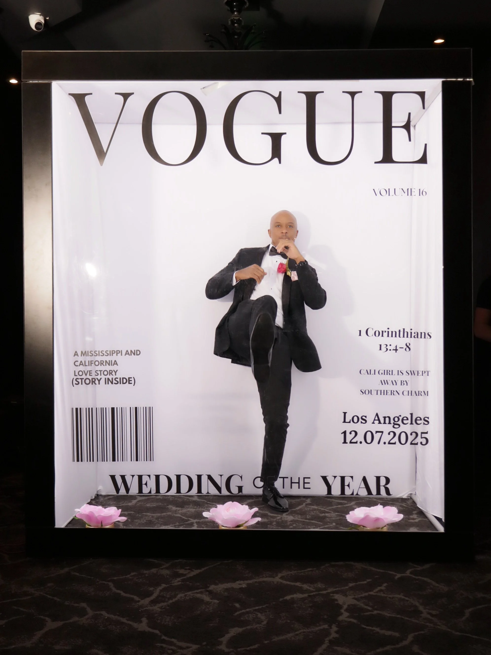 A magazine cover styled display with a man in a tuxedo sitting in a white box, mimicking Vogue magazine. The display features text about a wedding, a Bible verse, and the date December 7, 2025, indicating it's a wedding of the year celebration.