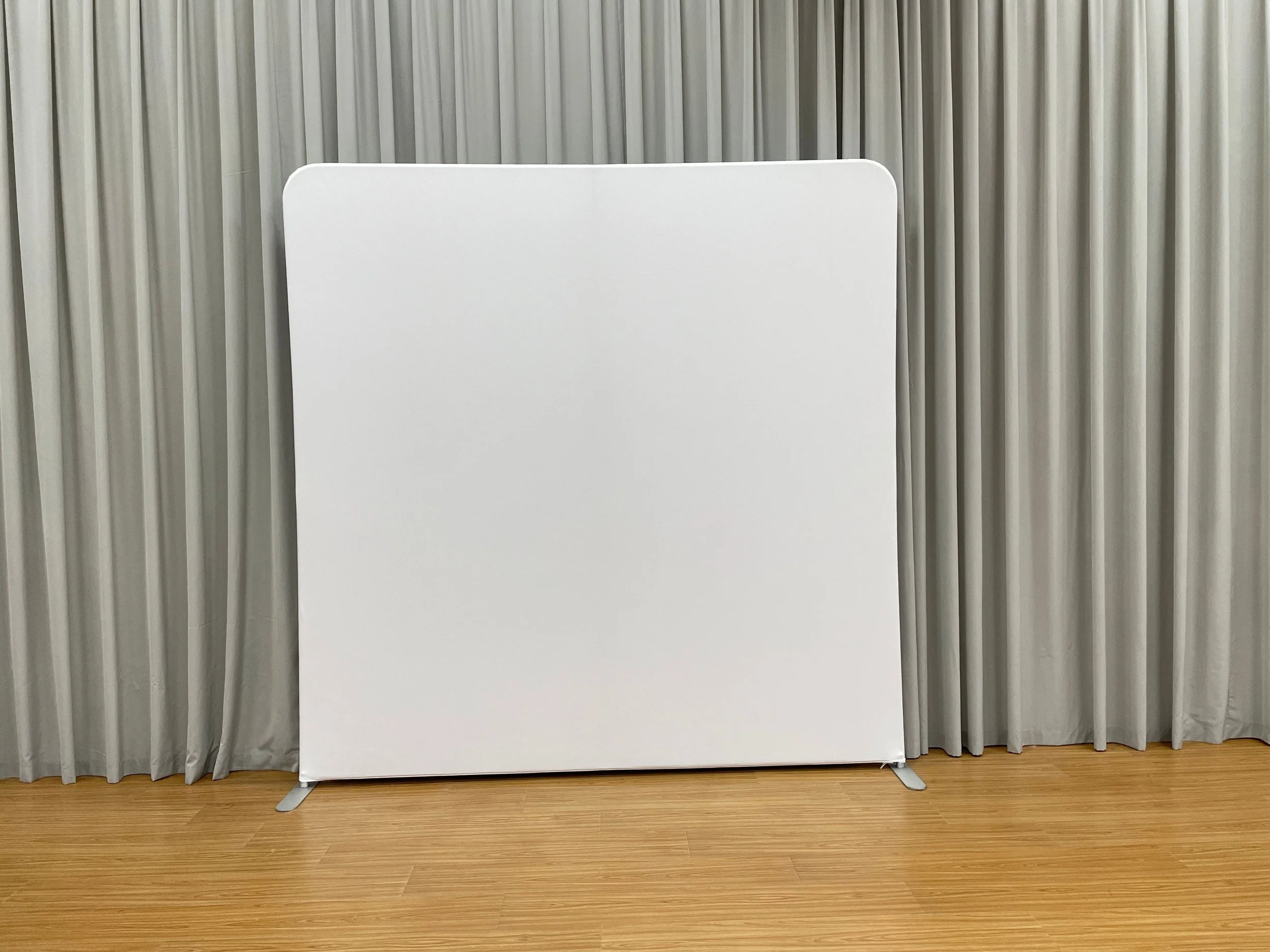 Blank whiteboard standing on a wooden floor, with beige curtains in the background.