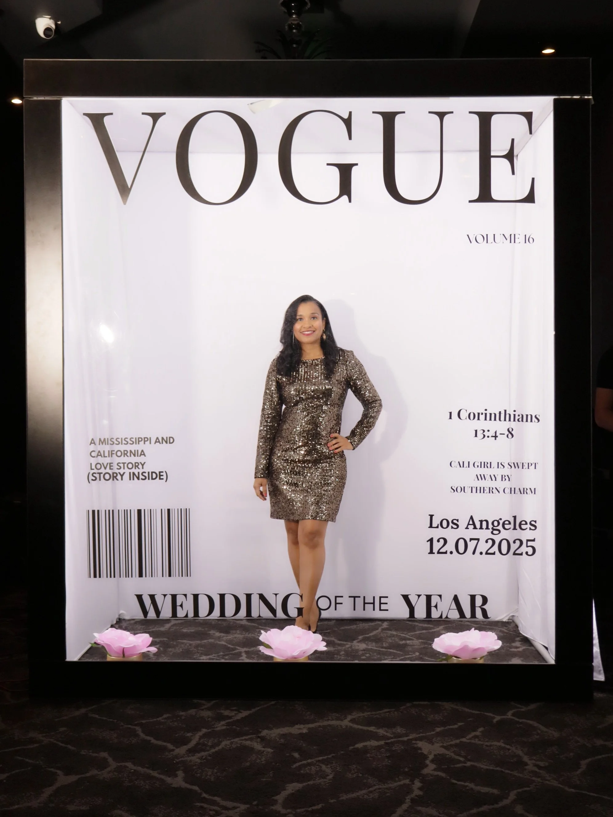 A large printed display with the Vogue magazine cover theme, featuring a woman in a black and gold sequined dress standing with one hand on her hip, inside a frame that resembles a Vogue magazine cover. The display includes text about a wedding, with