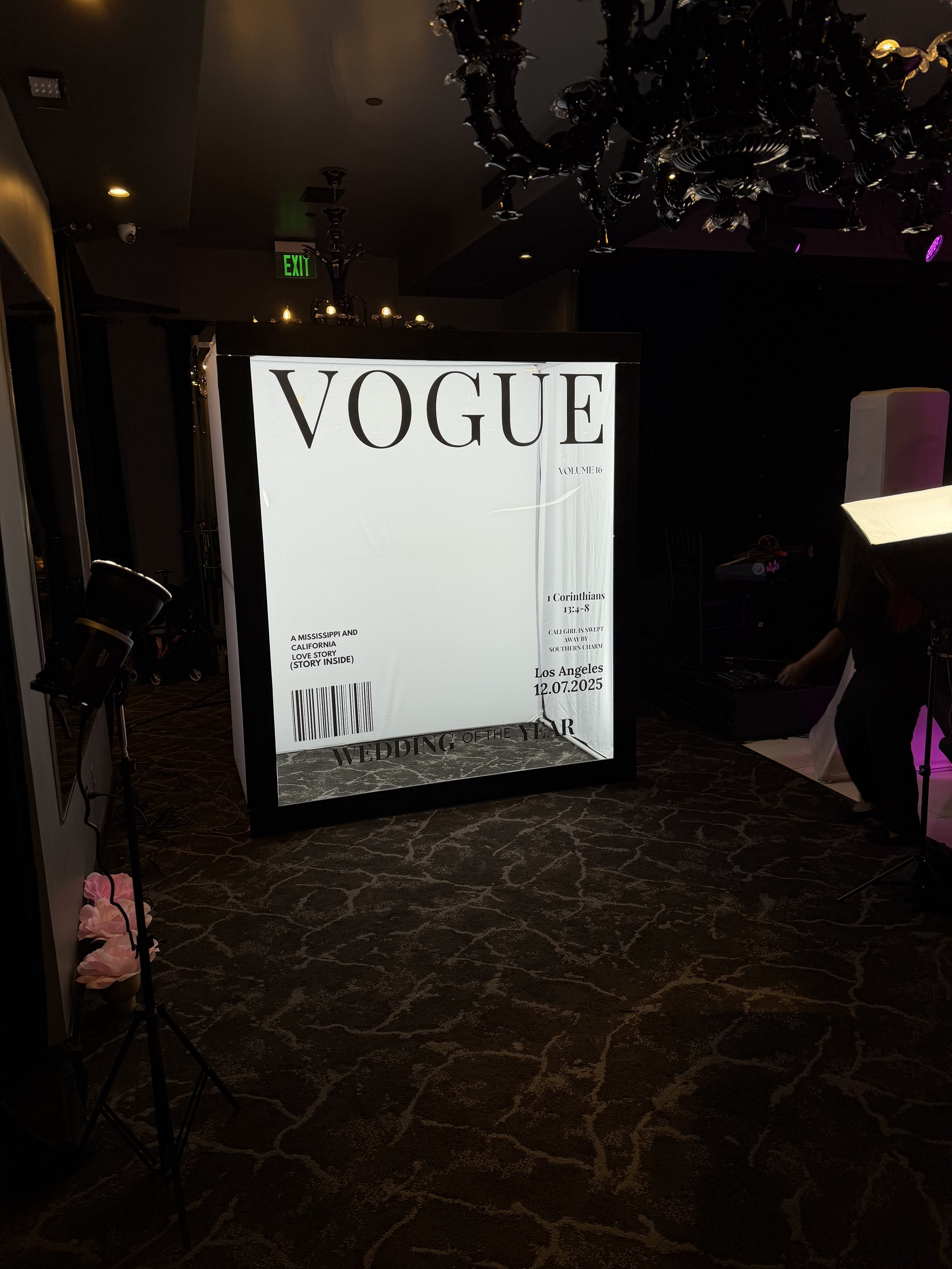 A large illuminated frame resembling a Vogue magazine cover with the words 'VOGUE' at the top, date 12.07.2025, and details about a wedding of the year event in Los Angeles, with various smaller text and design elements.